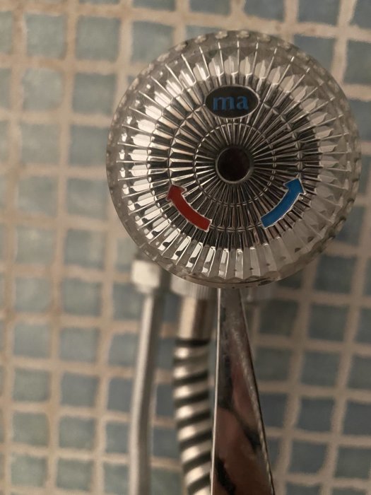 Handdusch med temperaturindikatorer mot kakelbakgrund, undrar om utbyte av packningar.