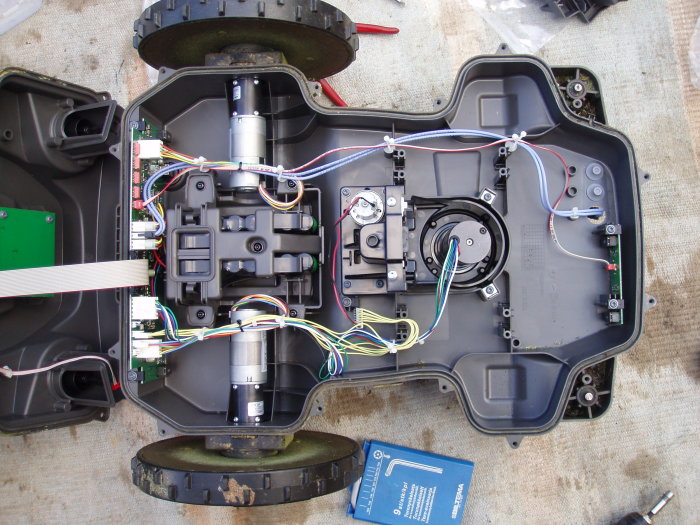 Öppen Husqvarna Automower 330x från 2015 med synliga interna komponenter, kablar och äldre batterier.