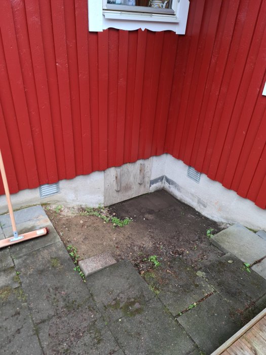 Ingång till krypgrund under hus med röd fasad, synlig gjuten sula och stenplattor som behöver avrinningslösning.