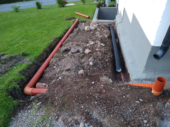 Nyligen installerade markavloppsrör bredvid ett hus för att leda bort takvatten.