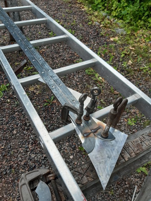 Aluminiumbalk för balkong med svetsningsutrustning och justerbara fästen på grusunderlag.