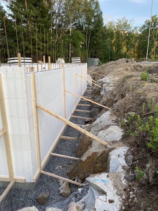 Konstruktionsområde med uppställda isolerade väggformar och stödstag inför gjutning.