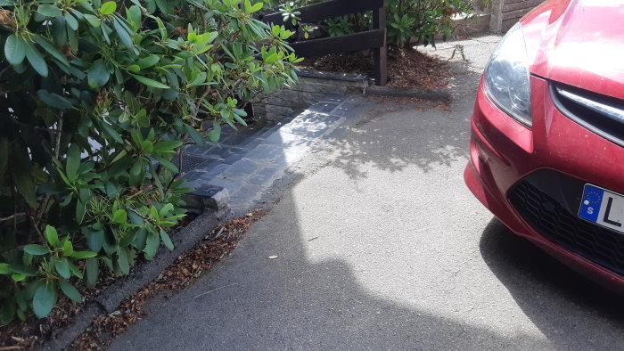 Uppfart med svag lutning och stentrappa, potentiellt översvämningsproblem vid regn.