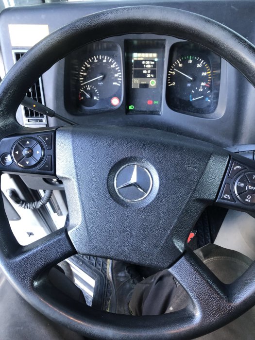 Ratt och instrumentbräda i en Mercedes-lastbil med synliga mätare och kontrollknappar.