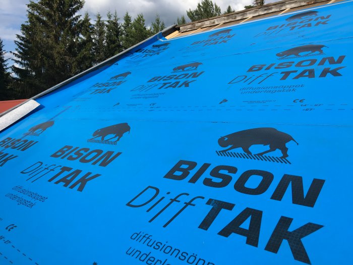 Ny lagd blå takduk med "Bison DiffTAK" tryck, infäst på taktavlor under renovering.