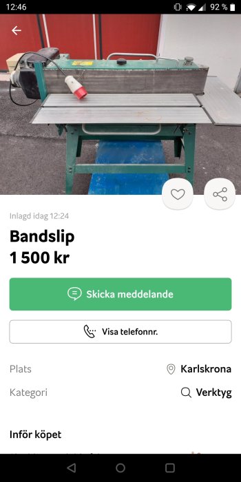 Bandslipmaskin till salu för 1500 kr, placerad utomhus framför röd vägg.