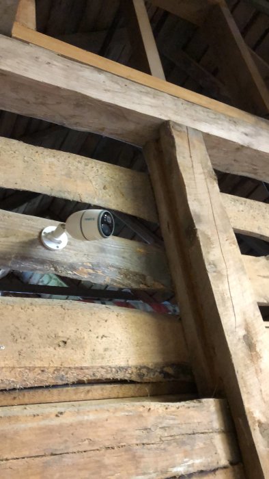 Reolink Go övervakningskamera monterad på träbjälke i lada.