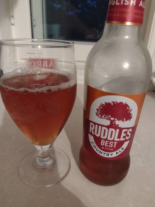 Alt: Ölglas fyllt med Engelsk ale bredvid en delvis tom flaskan av Ruddles Best Country Ale.