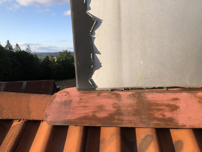 Närbild på tak med bristfällig tätning vid avloppsluftare, rostig vindskiveplåt och öppet utrymme under nocken.