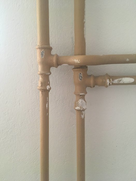 Gammal rörinstallation med förgrening och övergångar/bussningar på en vägg.
