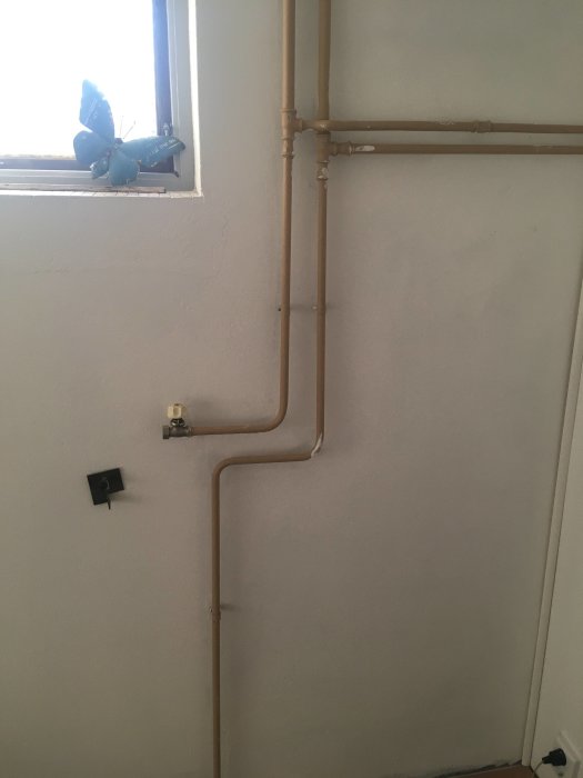 Kopparledningar på en vägg med förgrening och avstängningsventil, planerad för ombyggnad.