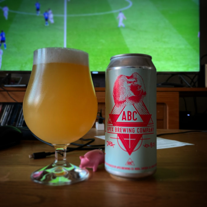 Ölglas och burk framför en fotbollsmatch på TV.