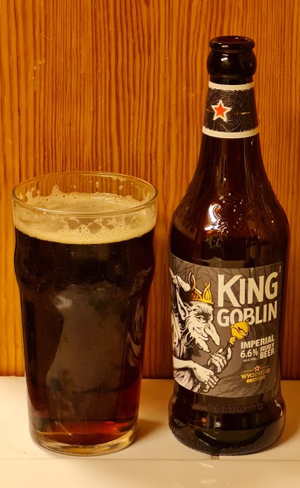 En flaska King Goblin öl bredvid ett glas fyllt med mörkt öl.