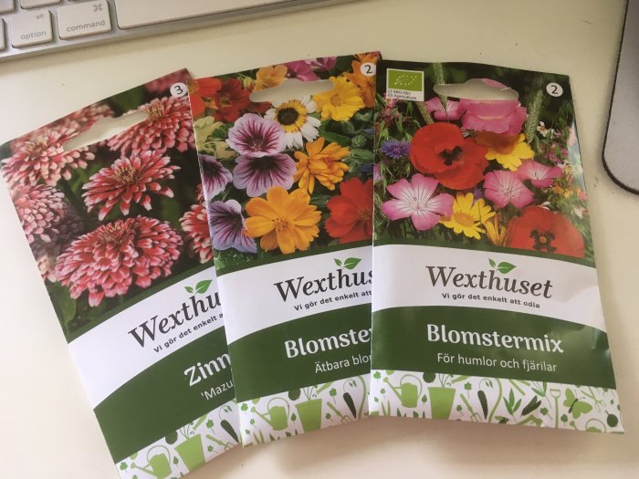 Fröpåsar för Zinnia 'Mazurkia', ätbart blomstermix och blomstermix för humlor och fjärilar på ett bord.