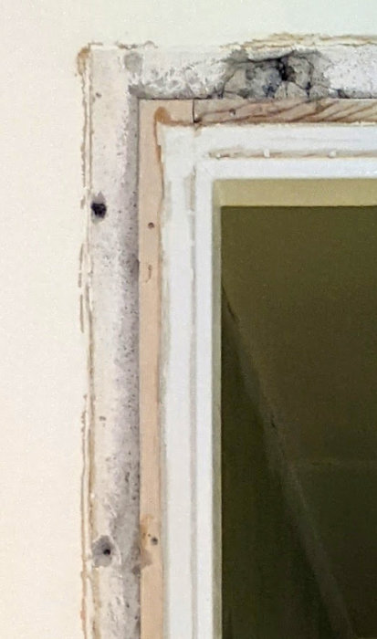 En demonterad dörrkarm i en 50-talslägenhet med synliga rester av gammalt foder och puts.
