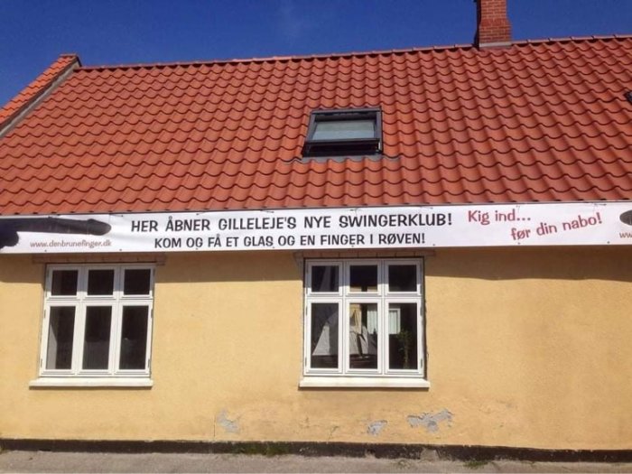Ett gult hus med rött tak och en banner som annonserar en ny klubb.