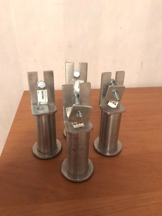 Tre nedmonterade metallben från en Sultan resårbotten med synliga skruvar och brickor på ett brunt underlag.