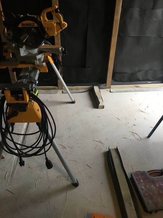 DeWalt kapsåg på stativ i ett pågående byggprojekt med träspån på golvet.