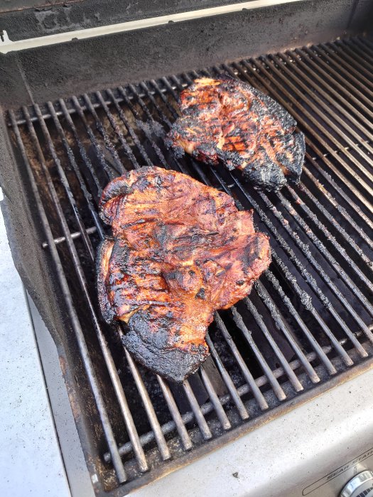 Två grillade flintastekar på en gasolgrill.