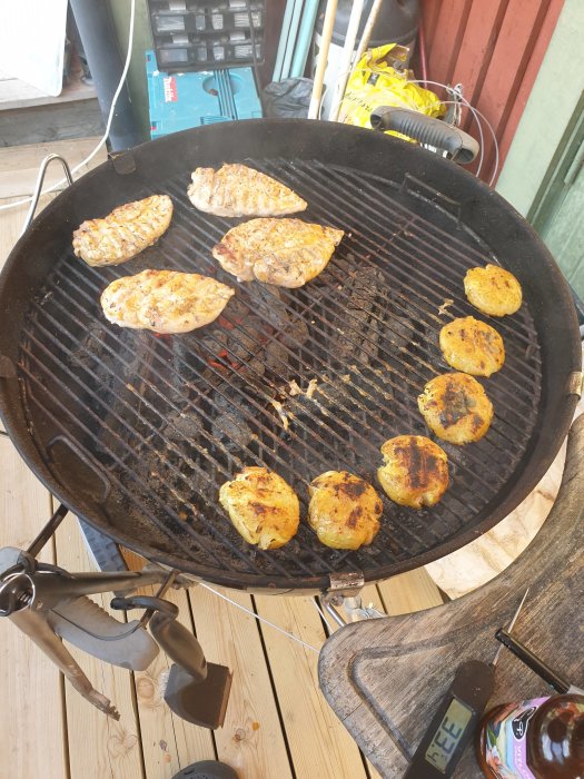 Grill med kyckling och potatis, kryddad med Caj Ps marinad, på en träaltan.