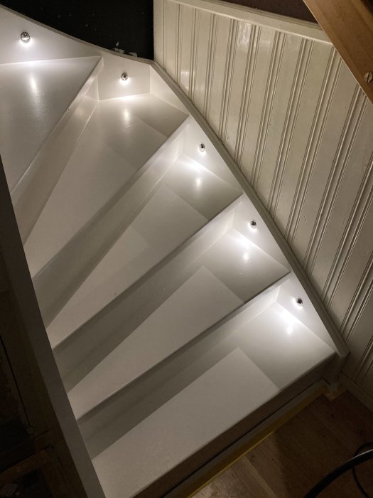 Vit trappa med inbyggd belysning på varje steg i ett hemmiljö.