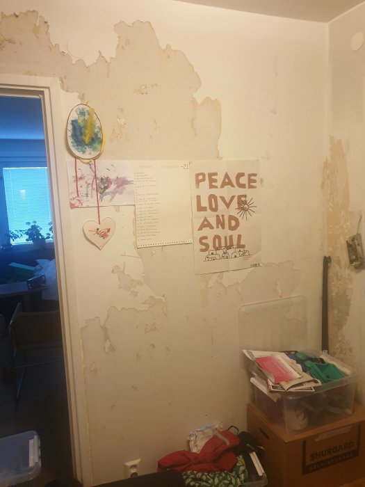 Vägg med delvis borttagen tapet och affischer, behöver renoveras.