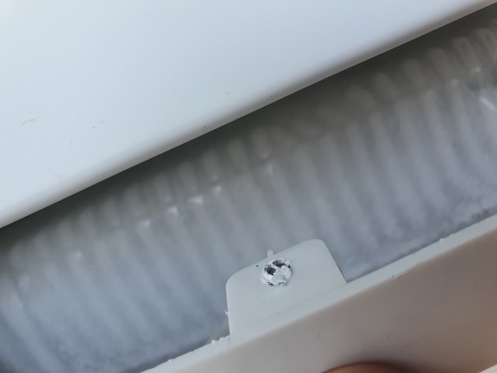 Isbildning på kylskåpets kylpaket med synlig fläkt och en hand som känner på den.