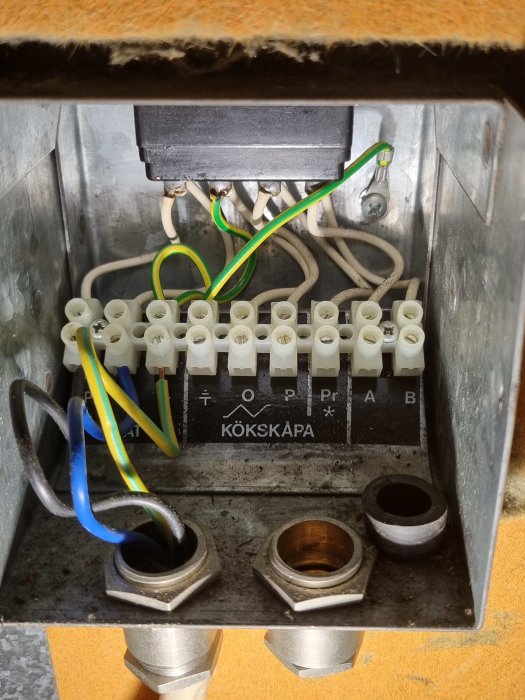 Öppet ventilationsaggregat med kopplingsdosa märkt "KÖKSKÅPA" och ledningar inkopplade, som tidigare anslöts till köksfläkt.