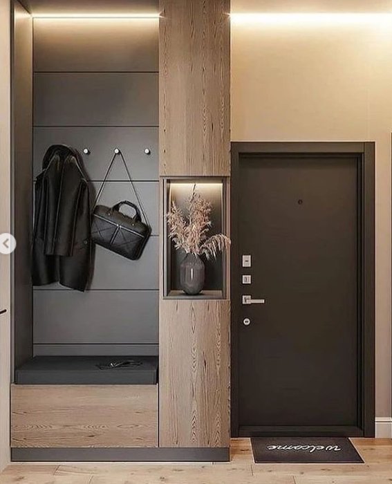 Modern hall med inbyggd specialgarderob i grått och trä, belysning, sittdyna, krokar och dekorativ vas.
