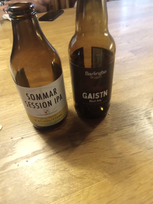 Två ölflaskor på ett bord, en märkt "SOMMAR SESSION IPA" och den andra "GAISTN Röd Ale".