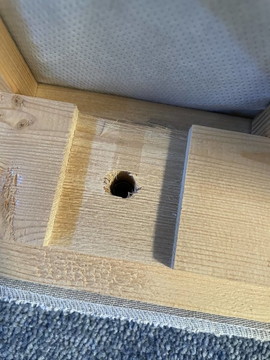 Hålet i träet på en sängstomme där en gänga är synlig djupare ner i hålöppningen.
