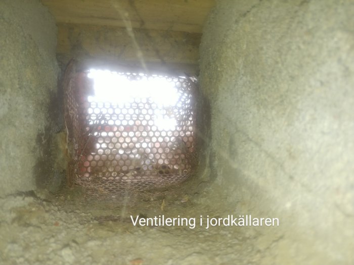 Gammal ventilationsöppning i jordkällare med mögelskador och smuts.