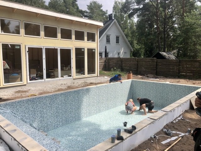 Installation av pool liner med slangar bredvid, i en trädgård nära hus.