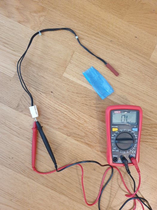 Multimeter ansluten till en termistor med blå tejp runt, för felsökning av frystemperatur.