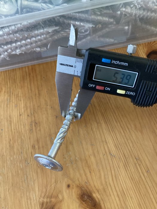 Skrivmått som mäter innerdiametern på en träskruv mot träbakgrund.