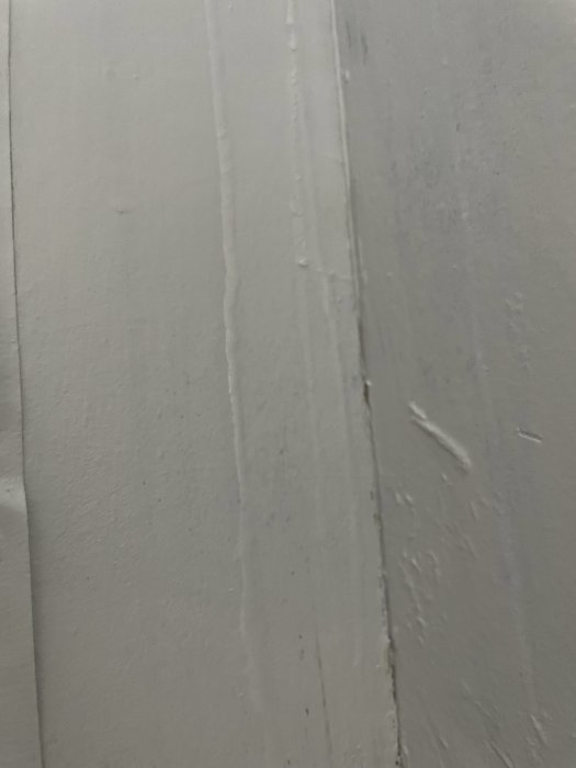 Vägg med synliga vattenskador och rinnande vatten längs med ett vertikalt hörn.
