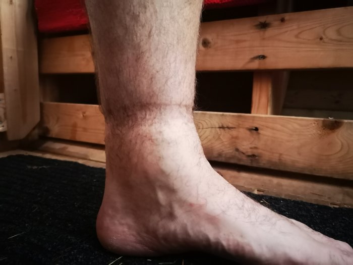 Svullen vrist efter en lång dags målningsarbete, framför trähyllor.