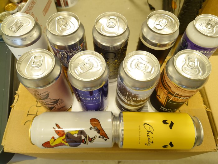 Sammansättning av ölburkar från Arpus, Northern Monk, Stigbergets, Apex, Duckpond och Equilibrium i en kartong.