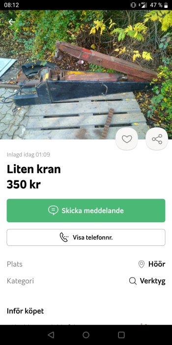 Begagnad liten kran till salu, placerad på marken med skogsbakgrund, till priset av 350 kr.