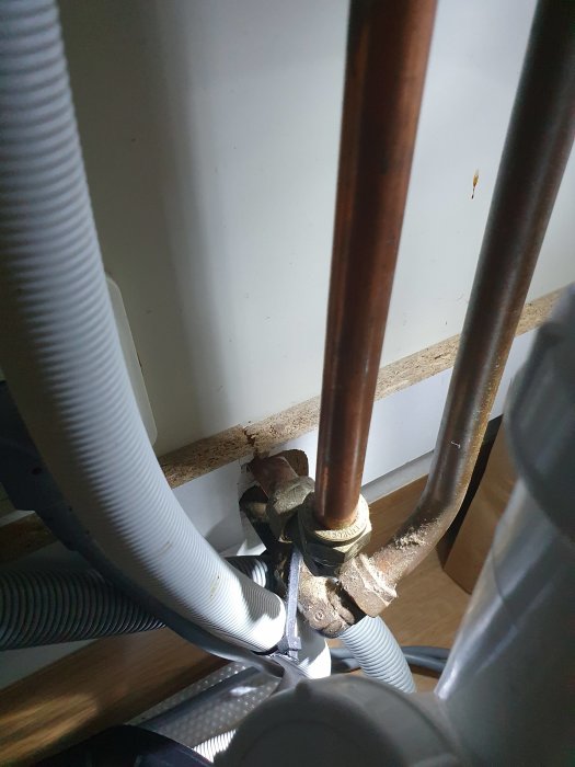 Rörsystem under köksbänk med synliga kopparledningar och avstängningsventil.