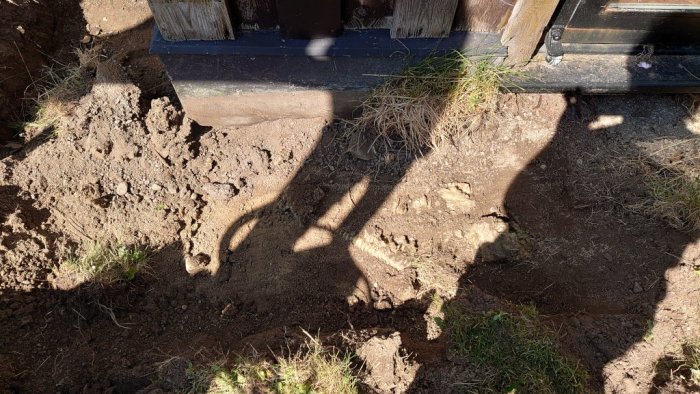 Grävd jord nära en husvägg avslöjar en gul markslang som misstänks vara starkström.