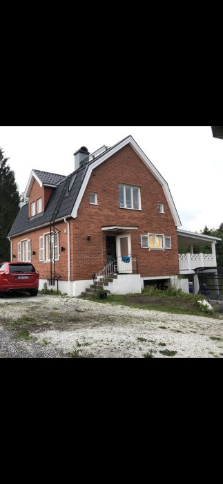 Tegelhus med sadeltak och vit entrétrappa, tänkt för L-formad tillbyggnad och glasad altan.