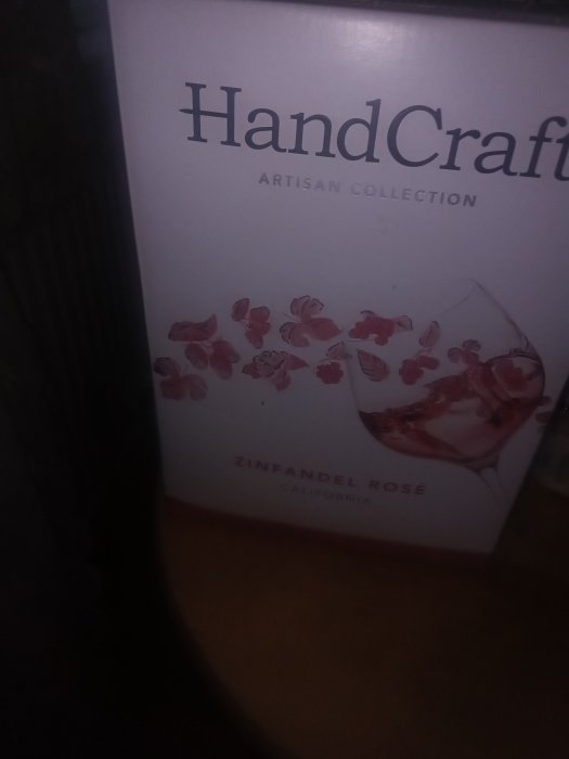 Flaska med etikett "HandCraft Artisan Collection Zinfandel Rosé" från Kalifornien på mörk bakgrund.