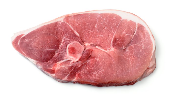 En skiva rå Iberico-karré på en vit bakgrund som understryker köttets kvalitet och marmorering.