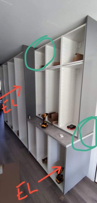 Vit bokhylla utan belysning, röda pilar visar elledningar, gröna cirklar markerar täckplatta och bänkskiva.