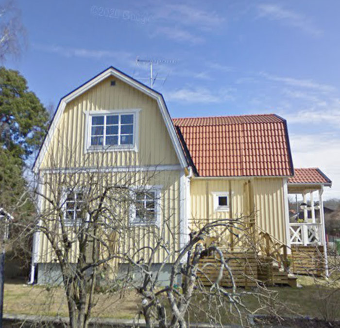 Gult hus med röd takpannor från street view, utbyggt med extra sektion och veranda.