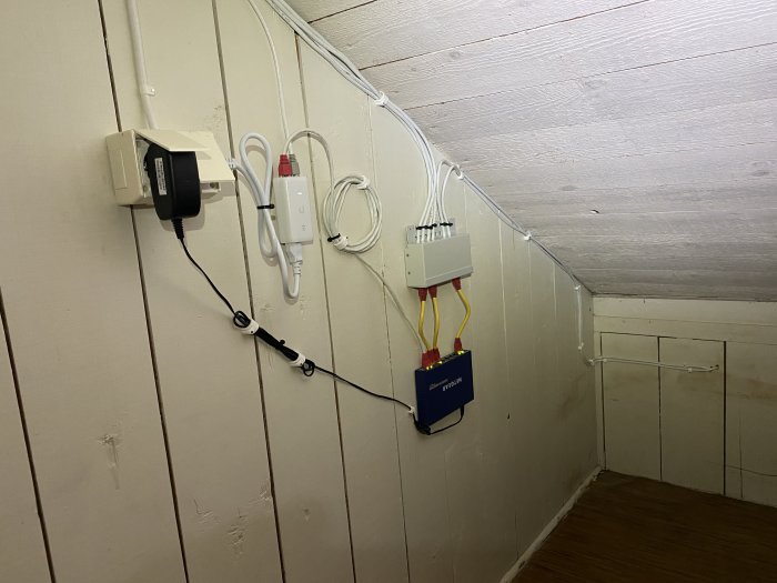 En ren och organiserad nätverksinstallation på en vind med kablar, nätverksuttag och Unify Lite 6 i taket.