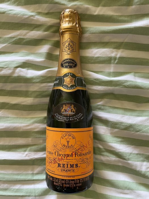 Flaska av Veuve Clicquot champagne, etikett markerar 1972, på randigt lakan.