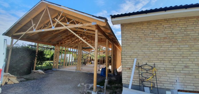 Konstruktion av trätakstomme på nybygge intill tegelhus med råspont och vindduk.