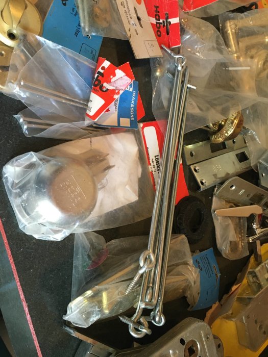 Osorterade byggdetaljer som lås, beslag och nyckelbrickor, några i förpackning.